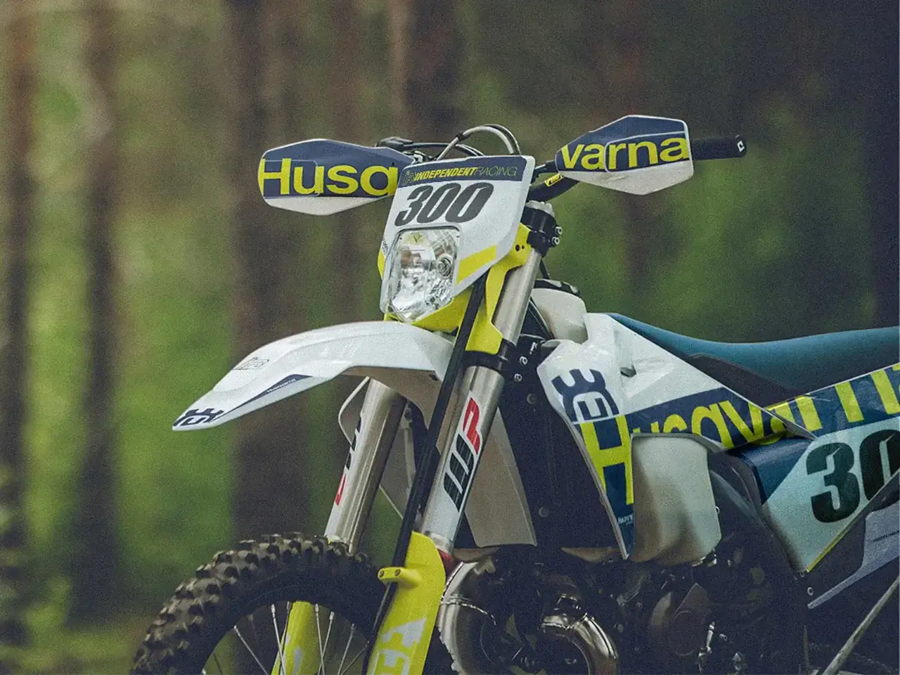Nahaufnahme eines Husqvarna Enduro-Motorrads mit Custom Dekor mit Waldhintergrund | Independent Racing