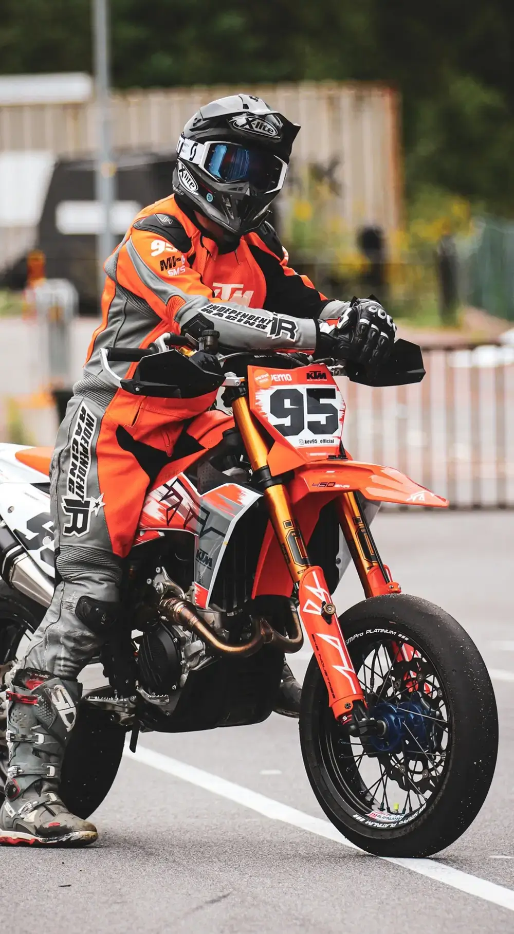Fahrer mit orangefarbenem Lederkombi auf Supermoto.