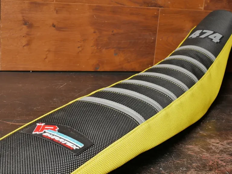 Gelb-schwarzer Sitzbankbezug mit grauen Rippen auf Werkbank platziert.