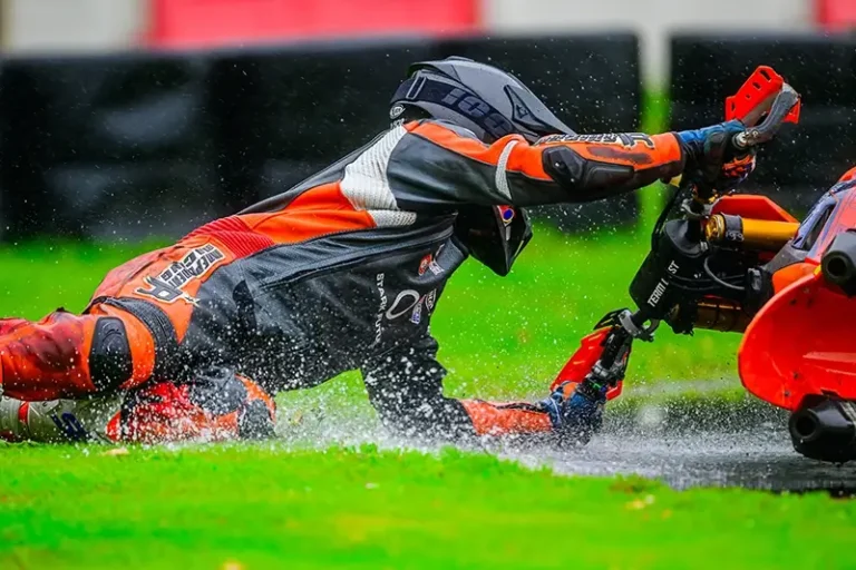 Ein Supermotofahrer in einer Independent Racing Lederkombi stürzt bei Regen.